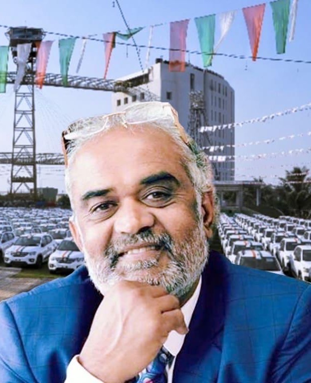 Savji Dholakia photographed in front of the company campus with rows of cars parked outside.