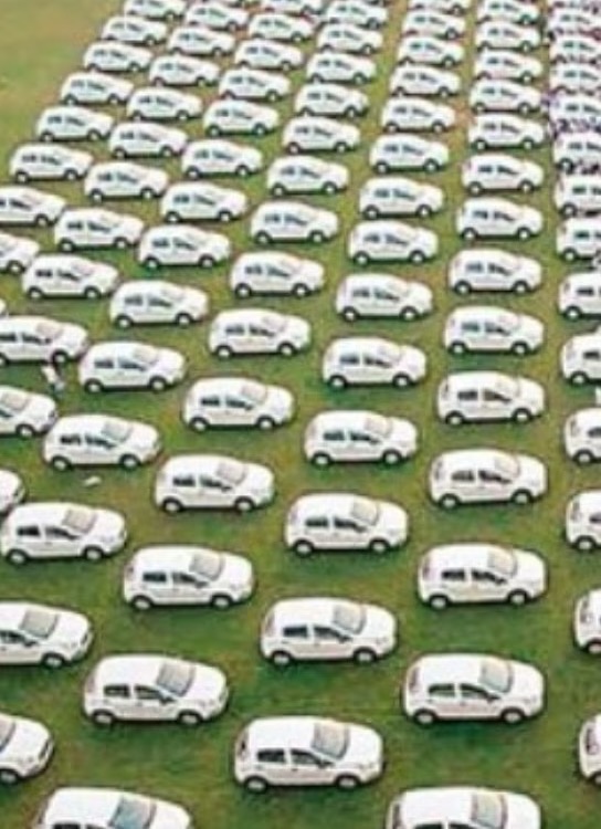 Aerial view of rows of identical white cars parked on a lawn.