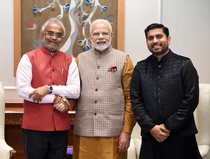 Savji Dholakia shaking hands with Prime Minister Narendra Modi, with a third guest standing alongside.